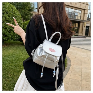 Detailed view of a silver metallic mini backpack with drawstring and bead charms