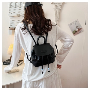 Detailed view of black PU leather mini backpack with flap and drawstring on a model