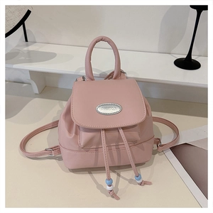 Detailed shot of a mini pink backpack featuring a silver metal logo plate and beaded drawstrings