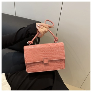 Detailed shot of pink faux crocodile skin texture and woven handle on small square handbag