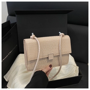 Detail of beige crocodile pattern handbag with silver metal buckle and knotted strap detail