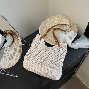 Chic hollow woven straw shoulder bag with brown leather handles and gold rivet accents