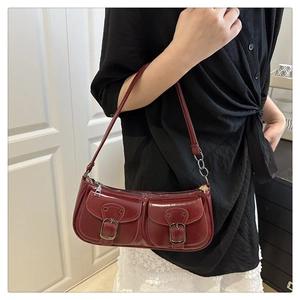 Detail of burgundy patent leather baguette bag featuring functional front pockets and silver chain