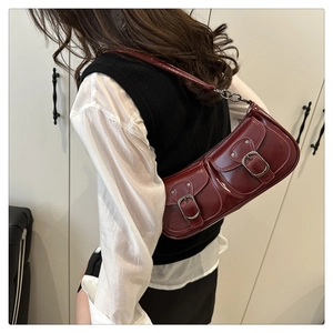 Detailed view of burgundy glossy shoulder bag featuring double flap pockets and metal chains