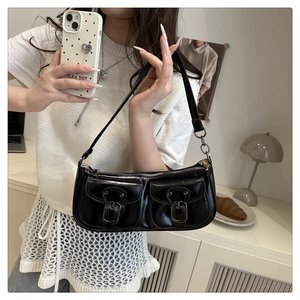 Detail of black glossy PU leather underarm bag with retro silver buckles and dual front pockets