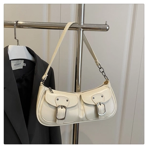 Detail view of cream baguette bag with metallic buckles and chain strap on hanger