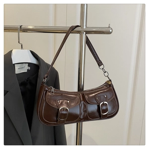 Detail of dark brown baguette bag with silver buckles and chain strap on a suit background