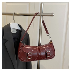 Detail of dark red faux leather baguette bag with dual front pockets and silver hardware