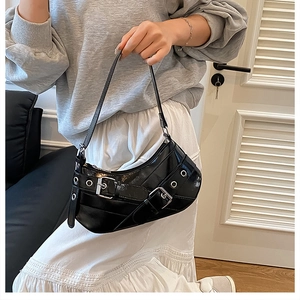 Detail of black glossy hobo bag with silver metal eyelets and punk style buckle straps
