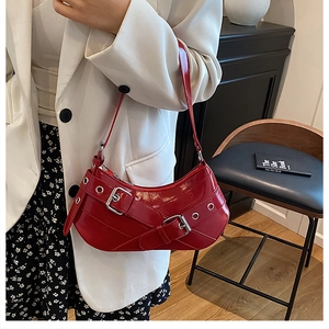 Red glossy patent leather shoulder bag featuring silver eyelets and buckle straps detail