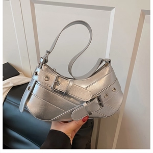 Detail of silver metallic underarm bag with punk buckled straps and grommet hardware