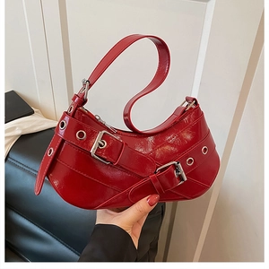 Close-up of red patent leather underarm bag featuring silver eyelet belt buckle details