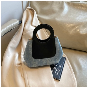 Detail of blue denim bucket bag with silver rhinestones and black round handle