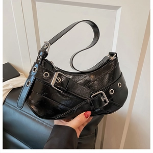 Detail of black glossy patent leather shoulder bag with silver metallic buckle straps