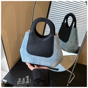 Detail of denim and black leather bucket bag with rhinestone studs and round hollow handle