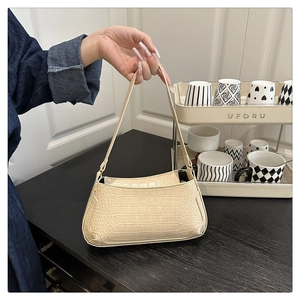 Detailed close-up of cream faux leather baguette bag with luxury crocodile texture