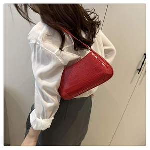 Detailed close-up of a red crocodile pattern baguette bag with a glossy leather finish