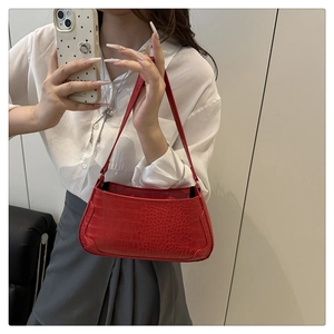 Detail of red crocodile texture on a crescent shoulder bag with high-quality stitching