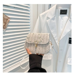 Close-up of woven saddle bag with delicate floral embroidery and metallic buckle clasp