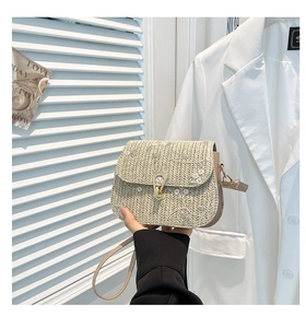 Detail of woven straw bag with white floral embroidery and metal horseshoe buckle clasp