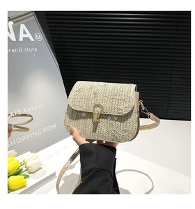 Detailed view of woven straw bag with floral embroidery and golden metal lock