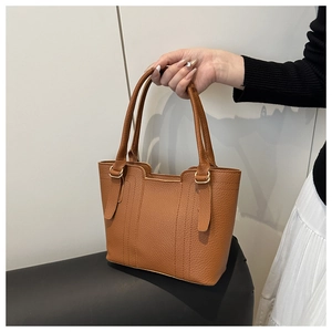 Detail of brown lychee grain leather tote bag with elegant golden hardware and stitching