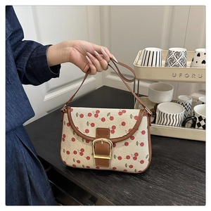 Detail of canvas shoulder bag with cherry print and brown faux leather strap buckle