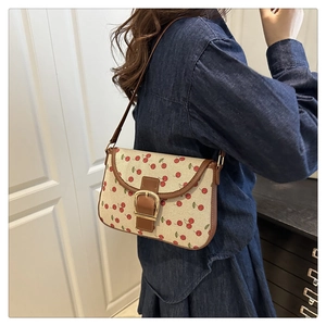 Detail of canvas shoulder bag with cherry print and brown leather buckle strap
