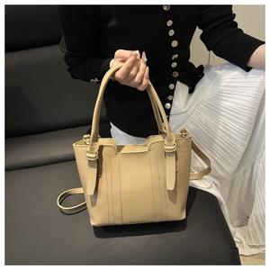 Detail of beige leather bucket bag with litchi texture and detachable shoulder strap