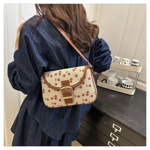 Detailed view of cherry print shoulder bag with brown leather trim and gold buckle closure