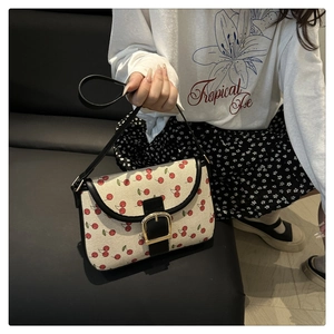 Detail of vintage cherry print shoulder bag with black strap and golden buckle closure