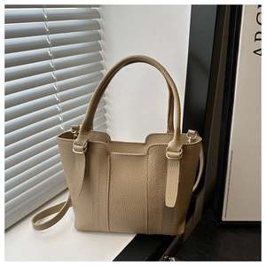 Detailed macro view of beige lychee grain leather tote bag with gold metal buckles