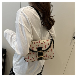 Close-up of stylish cherry print underarm bag with gold hardware worn by a model