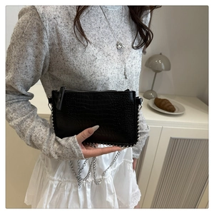 Detail of black crocodile texture handbag with silver bead trim and metallic chain