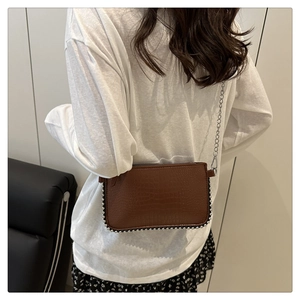 Detailed macro view of a brown crocodile pattern shoulder bag with metallic bead trim