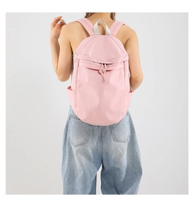 Rückansicht des Modells mit hellrosa Nylon-Rucksack mit Kordelzug-Reißverschlusstasche