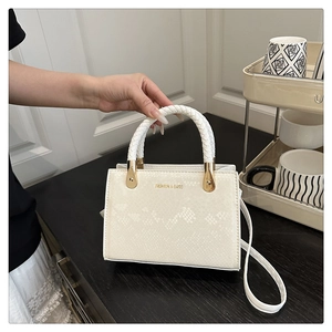 Close-up of white faux snake texture handbag with gold hardware and fashion lettering