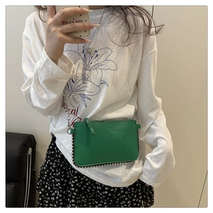 Detail of green crossbody bag with lychee leather texture and silver bead studs