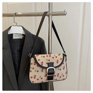 Detail of canvas shoulder bag with cherry print, black leather trim and gold buckle