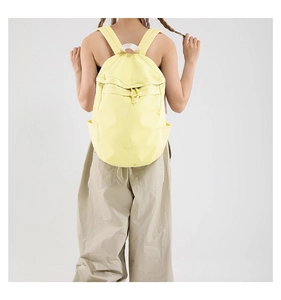 Rückansicht eines Modells mit hellgelbem Canvas-Rucksack und Kordelzugverschluss
