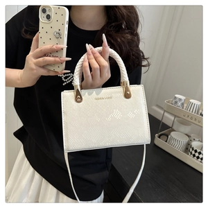 Detail of white embossed snake-skin pattern bag with woven handles and gold hardware