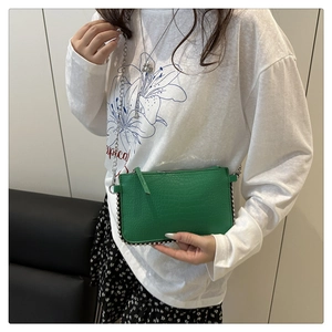 Détail du sac bandoulière vert effet crocodile avec chaîne argentée et clous métal
