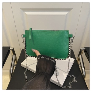 Detail of green crocodile embossed texture leather bag with silver studs and chain