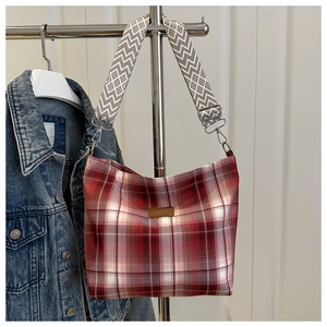 Detail of red checkered canvas hobo bag with wide geometric strap and leather fashion patch