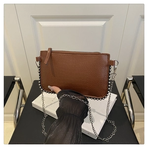 Detail of brown crocodile pattern shoulder bag with silver studs and chain strap