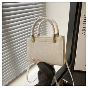 Detail of cream snake-texture crossbody bag with woven handles and gold hardware