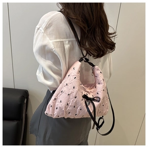 Detail of pink pleated shoulder bag with black bows and heart pendant on model