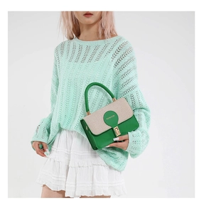 Dettaglio della borsa squadrata verde con patta in tessuto beige e chiusura metallica