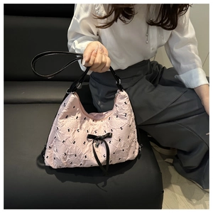 Detail of pink ruffled shoulder bag with black bows and silver heart pendant charm
