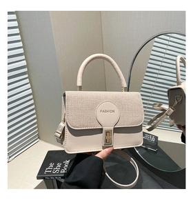 Dettaglio borsa beige con patta in tessuto intrecciato e chiusura con fibbia dorata